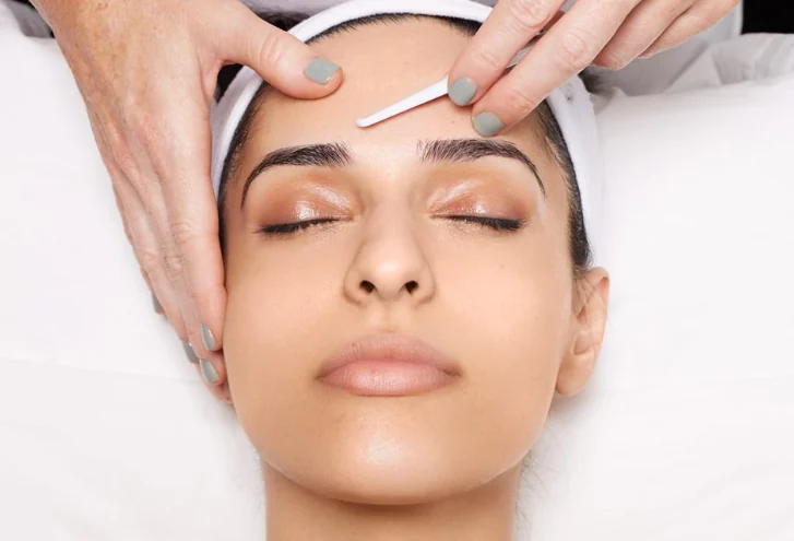 Relaxed client receiving a dermaplaning facial treatment