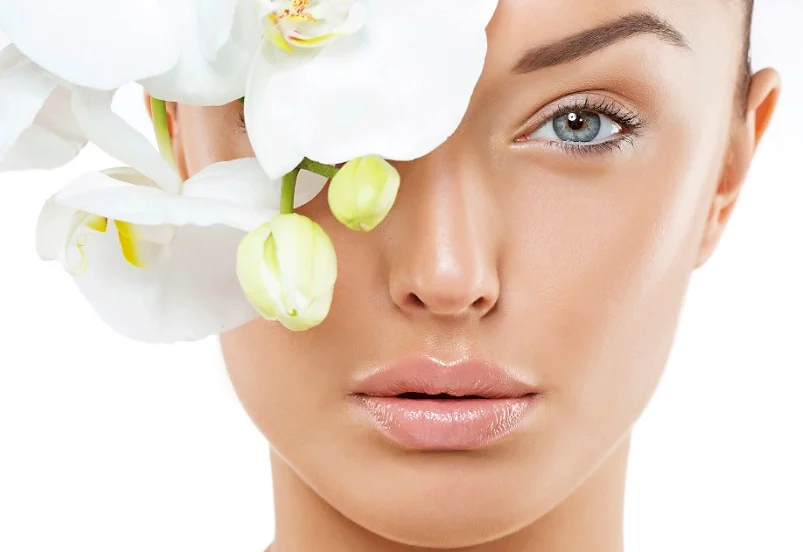 Woman with radiant skin holding white orchids